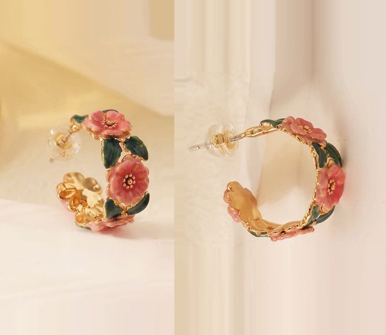 A pair of gold-colored French style floral hoops earrings with pink and green details, displayed against a white background.